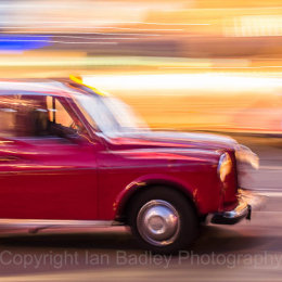 Red London taxi moving at night