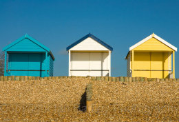 Three beach huts against a blue sky at Calshot, Hampshire, England