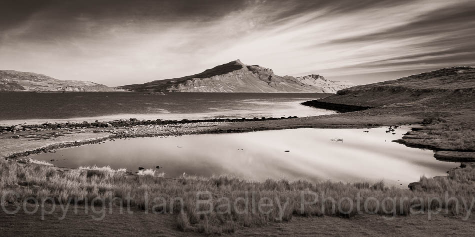 Sky streaks and view over pond and sea towards the Totternish Ridge, Isle of Skye, Scotland