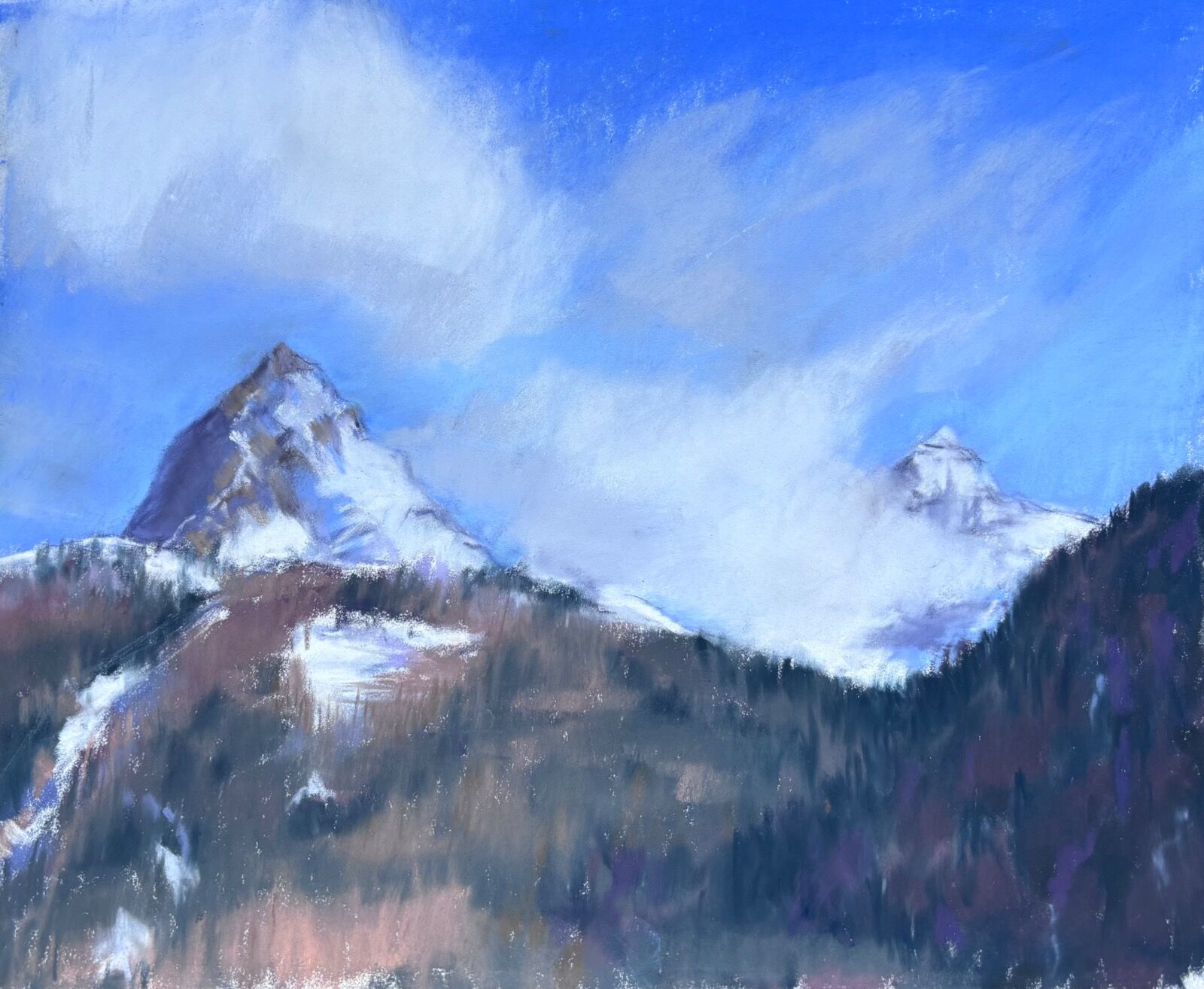 View from the balcony of the hotel looking up the mountains with pine forests and snow topped peaks