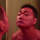 Junger Mann mit roten Kopf betrachtet sich im Spiegel