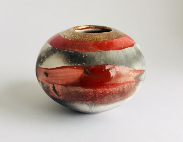 Red smoke-fired pot with gold lustre.