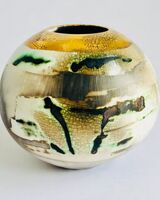 Burnished smoke-fired ceramic pot with gold lustre.