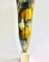 Tall smoke-fired pot with gold lustre on a stand.
