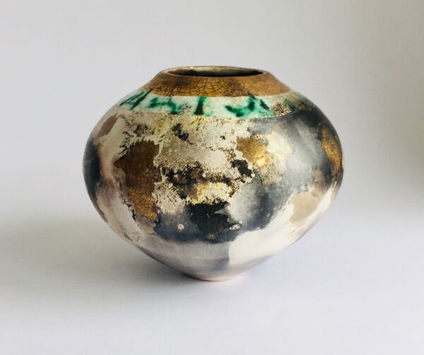 Round smoke-fired pot with glaze and gold lustre.