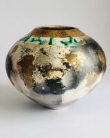 Round smoke-fired pot with glaze and gold lustre.