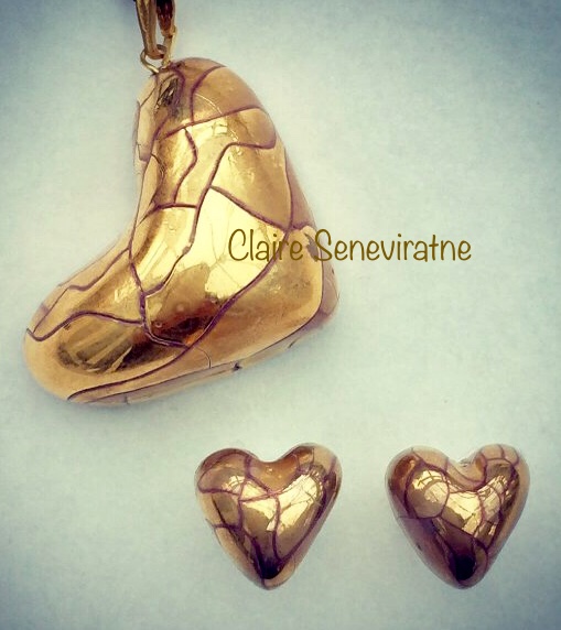 Gold lustre heart pendant hung from side with gold heart studs.