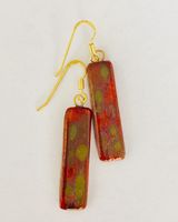 Red rectangular ceramic earrings with matt gold patterns.