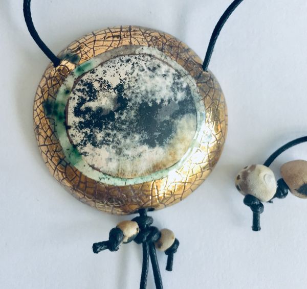 Round smoke fired pendant with gold.