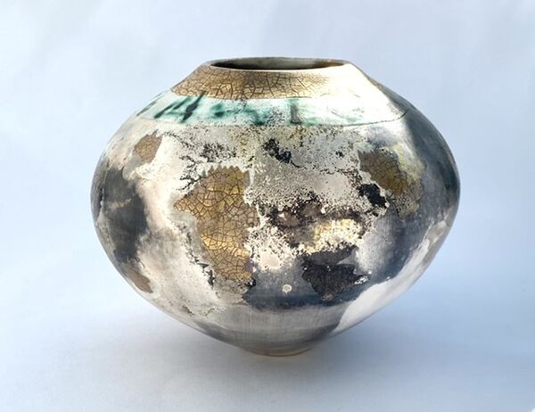 Round smoke-fired pot with glaze and gold lustre.
