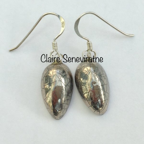 Small silver teardrop earrings with a crackle glaze.