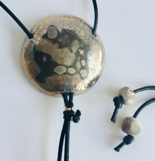 Round silver pendant with crackled textures.