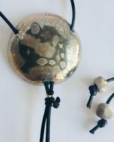 Round silver pendant with crackled textures.