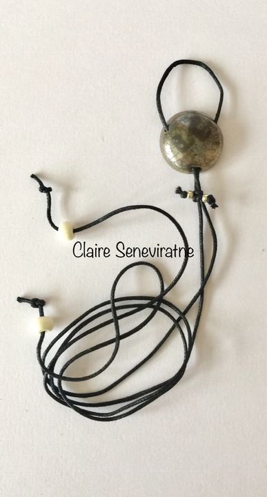 Round silver pendant with crackled textures.