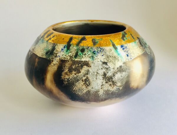 Burnished smoke-fired ceramic pot with gold lustre.