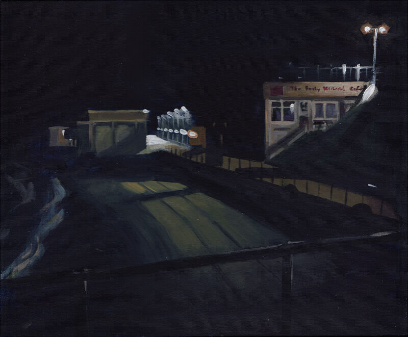 A night scene looking down on the beach, with a cafe in the background, faintly illuminated by streetlights
