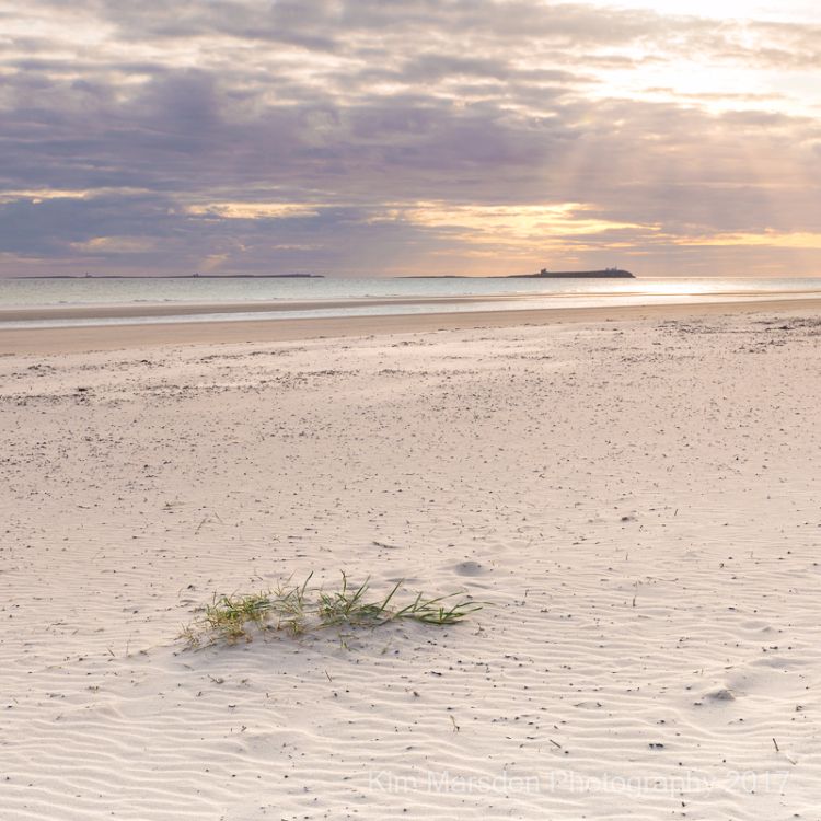 Early morning sun breaking through over Farne Islands from Bamburgh beach
