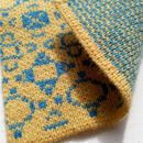 close up of yelllow knitting with blue motifs