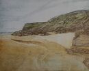Castlerock A beach with rocks at the far end and to the right. There is a stream of water across the sand.