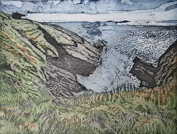 looking out to sea with rocks sloping to the left and right, covered partly in grass.  Forground isgrassy