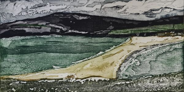 diagonal strip of sand between two green seas. Dark mountains in the background and green flora in the foreground