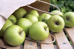 Granny Smith Apples spilling out of paper bag
