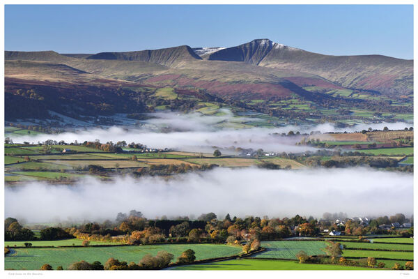 First Snow on the Beacons. Llangorse Lake and the River Usk shrouded in mist with Pen y Fan and Corn Du in the Brecon Beacons showing the approach of winter with the first light dusting of snow on their peaks.