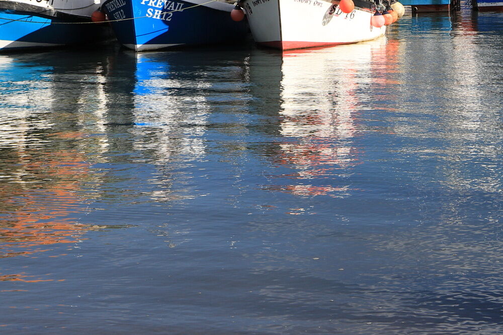 Reflections of fishing boats in the water at Scarborough Harbour