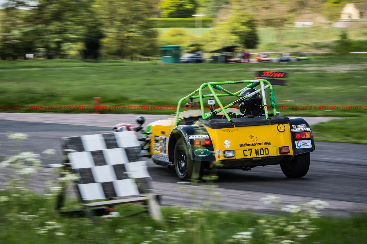 Yellow Caterham 7 at speed past the chequered flag at shenstone sprint course