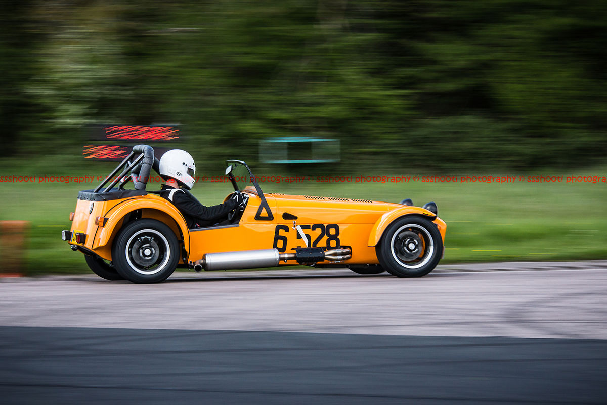 Orange Caterham 7 at speed through flag pole corner at shenstone sprint course