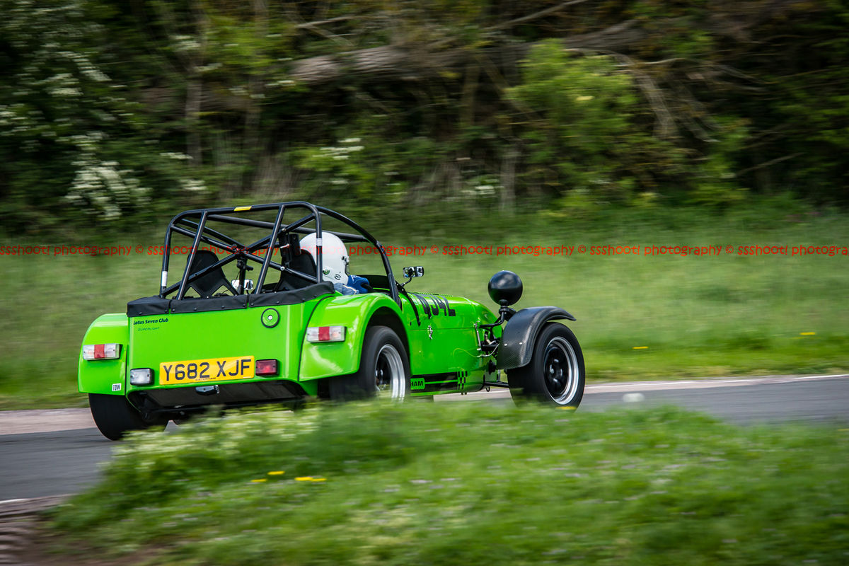 Bright green caterham 7 exiting flagpole corner at curborough sprint course