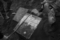 3 men measure the unearthed tombstones