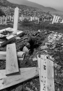 Grave digger stands in a grave which he dug up, Sarajevo view in the background