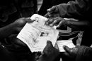 Hands of African refugees hold a paper document with a photo on it