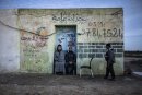 2 young unemployed men sit in front of the building, the third one walks beside, Tunisia