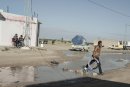 Tunisian man with a round object through a puddle in the middle of the village