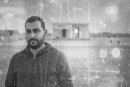 g unemployed man portrait, derelict building in the background