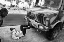 A refugee from Africa, lying on the ground stops the military truck