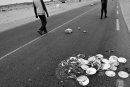 Discarded plates with food lying on the road while to man walk in the distance