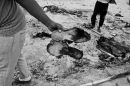 Refugee holds a pair of  burnt shoes