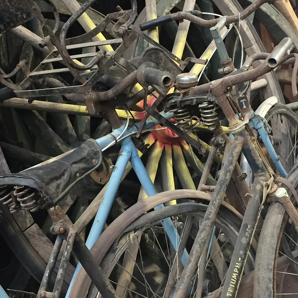 A stack of old bicycles leaning against a wall at a reclamation centre