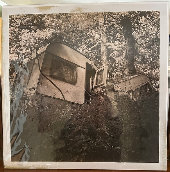 Black and white photographic print of a crushed caravan