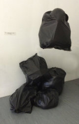 Black bin liners filled with paper and polystyrene and hung from the ceiling.