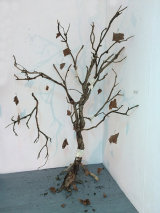 A dead tree, bandaged where cracked, with broken branch and leaves attached by invisible thread