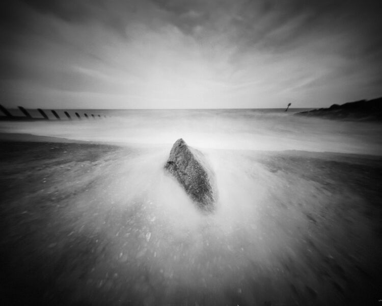 Rock on beach being smashed by incoming waves